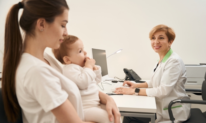 Friendly female pediatrician receiving parent with child in her office.