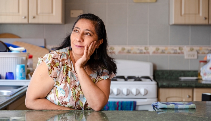 Hispanic woman in the kitchen of her thinking-smiling.