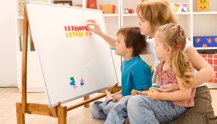 Kids learning the numbers with their mother and a magnetic board.