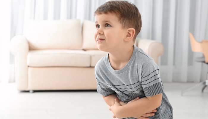 Little boy suffering from nausea in living room.