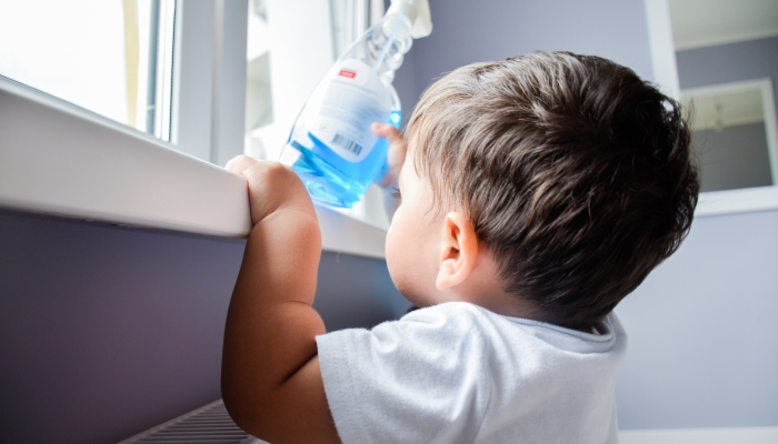 Little latin boy reaching a toxic cleaning product.