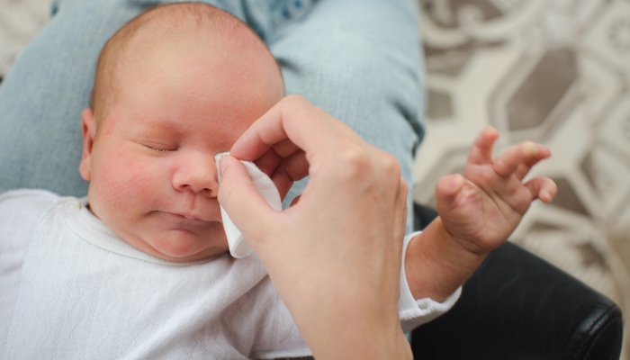 Mother cleaning eyes of a newborn baby.