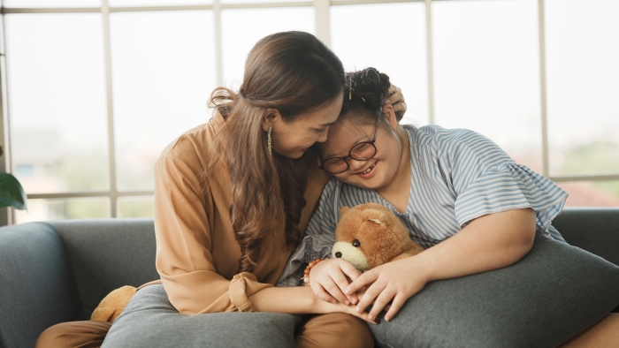 Mother supporting sweet down syndrome daughter to learn and relax from the internet.