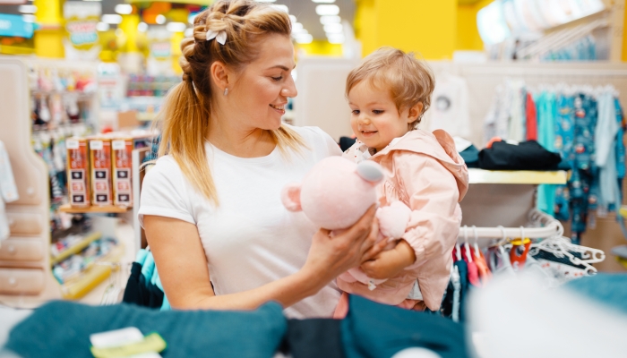 Mother with daughter choosing plush dog in store.