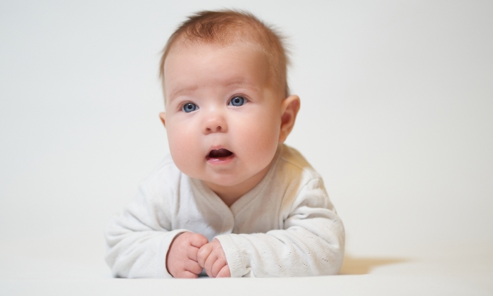 Portrait of an infant with its mouth open against a white background.