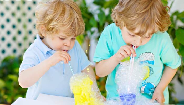 Two little boys making experiment with colorful soap bubbles and water.