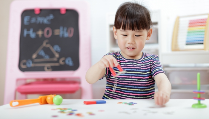 Young girl play magical magnet experiments at home for homeschool.