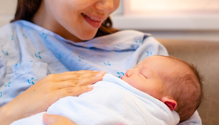 A happy mother holding her newborn baby after giving birth in the hospital.