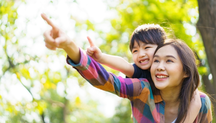 Asian woman and boy playing and walking around the park together.