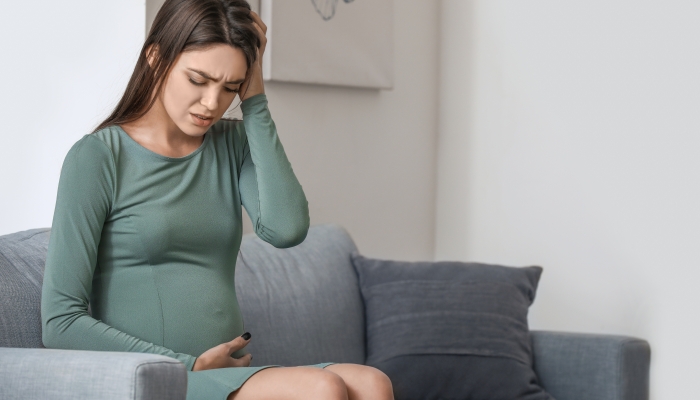 Depressed young pregnant woman at home.