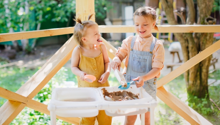 Happy sister kids play with sand and water in sensory baskets.