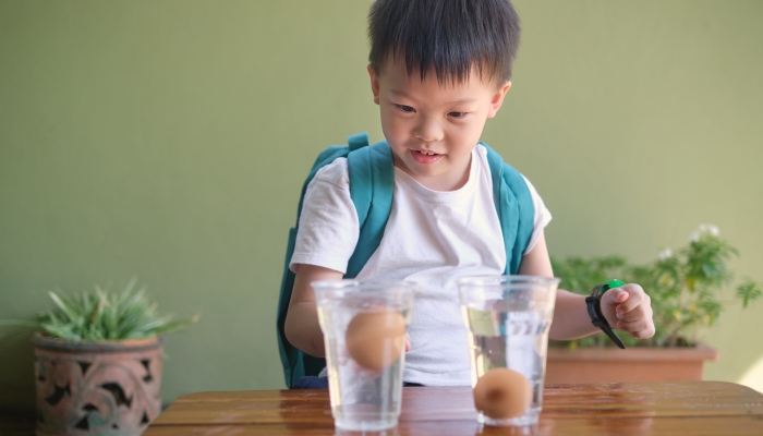 Happy smiling excited little Asian school kid studying science.