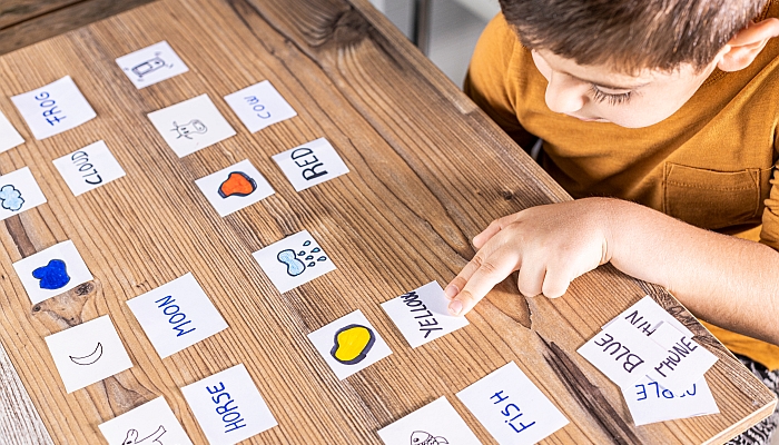 Little kid playing with cards of words and pictures.
