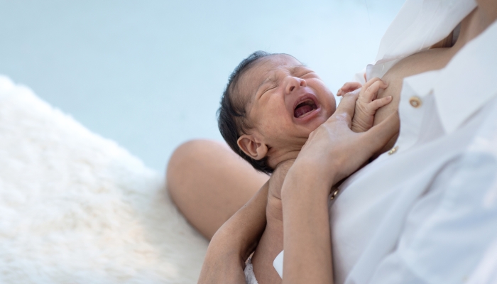 Mother breastfeeding the crying newborn baby.