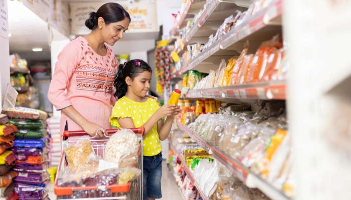 Mother with daughter looking product while shopping at supermarket.