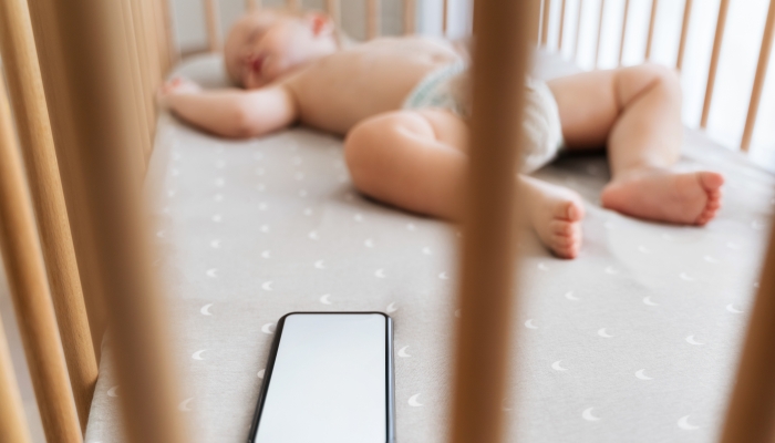 Selective focus of little boy in crib falling asleep with help of application for baby sleep.