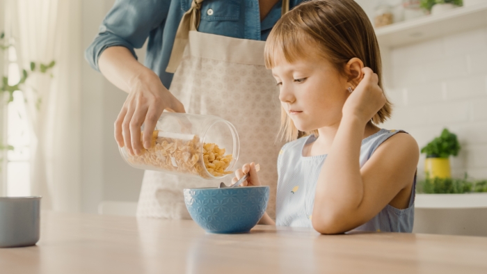 Young Beautiful Mother Pours Cereal into Bowl.