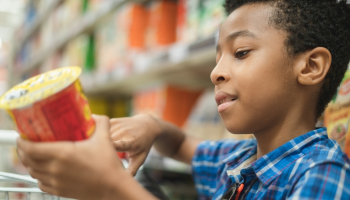 Young afro American kid reading chips label on a supermarket mall.
