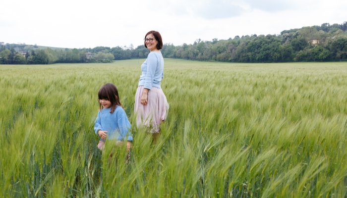 Smiling mother and daughter standing in the field of wheat.