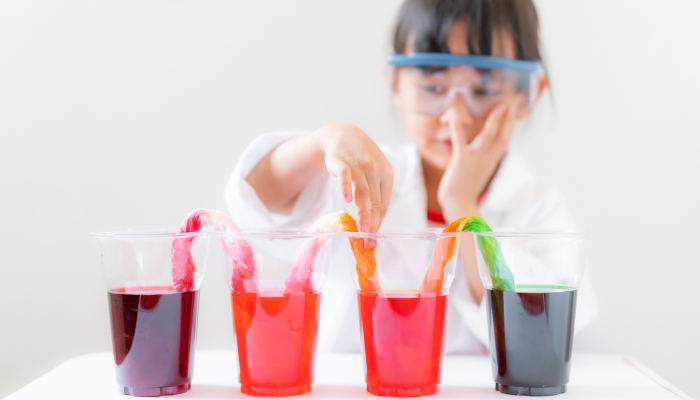 A 4 years old asian little girl is learning about color changing walking water experiment.