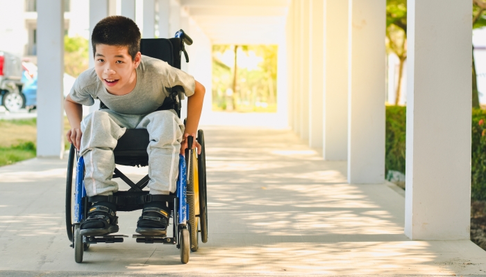 Asian special child on wheelchair is smile happily on ramp for disabled people.