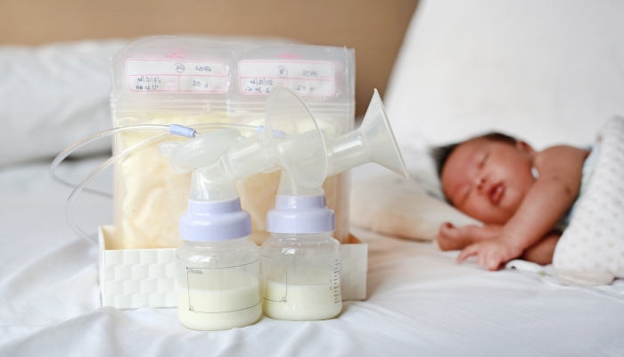 Automatic breast pump and Frozen breast milk in plastic bag on the bed.