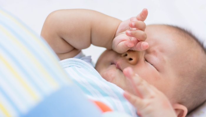 Baby rubbing it's eyes, feeling sleepy.