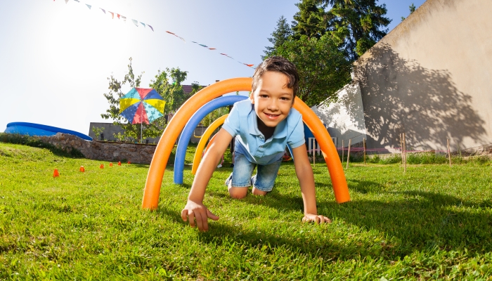 Boy pass under course of barriers on his fours.