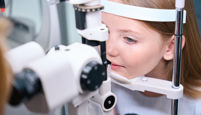 Child having his eyes checked with ophthalmic equipment.