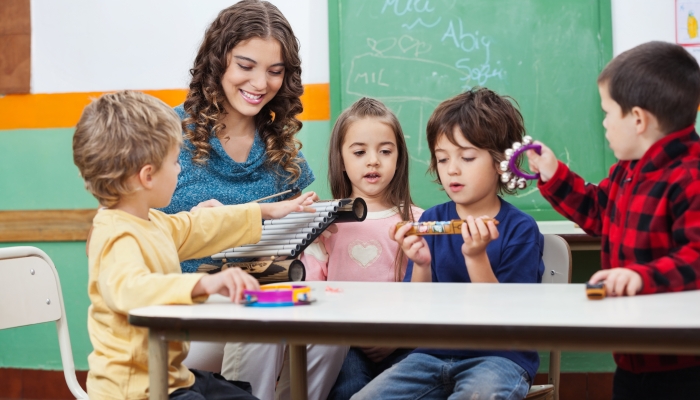 Children and teacher playing with musical instruments in preschool.