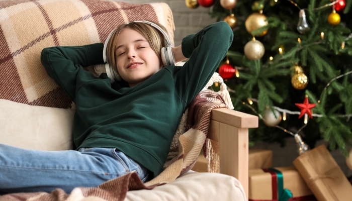 Cute little boy in headphones lying at home on Christmas eve.