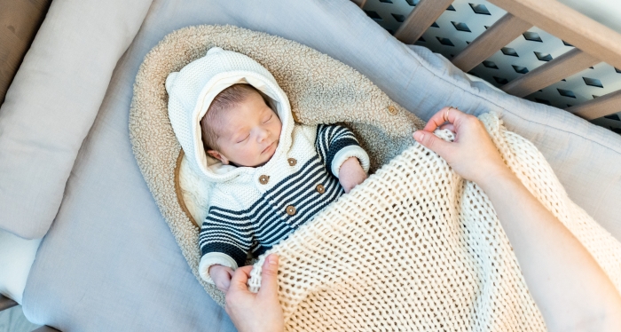 Cute newborn child sleeps wrapped baby blanket.