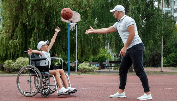 Teacher plays with his disabled student on the sports ground.