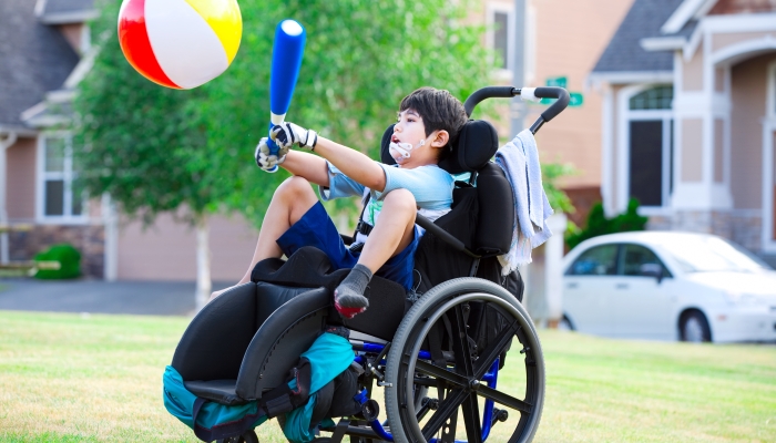 Disabled little boy playing ball in the park.