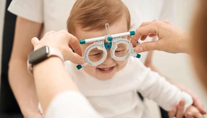 Eye specialist preparing little patient for visual acuity test.