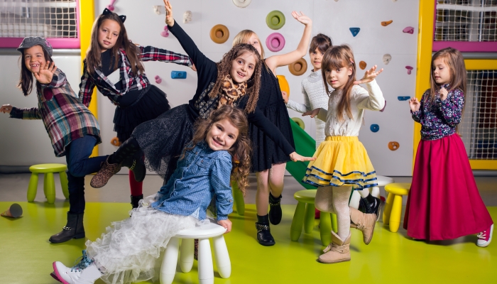 Group of happy preschoolers dancing in playroom.