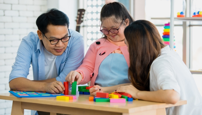 Happy Asian family father mother with a handicapped daughter with down syndrome play together.