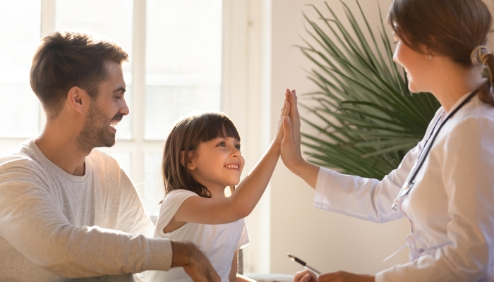 Healthy happy child girl giving high five to female caring doctor celebrate good checkup medical result.