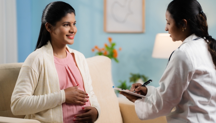 Indian doctor or nurse counseling pregnant woman at home by writing report at home.