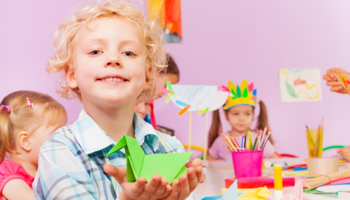 Kids in kindergarten make origami.