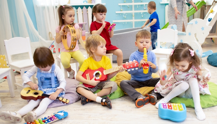 Kindergarten teacher with children sitting on the floor having music class.