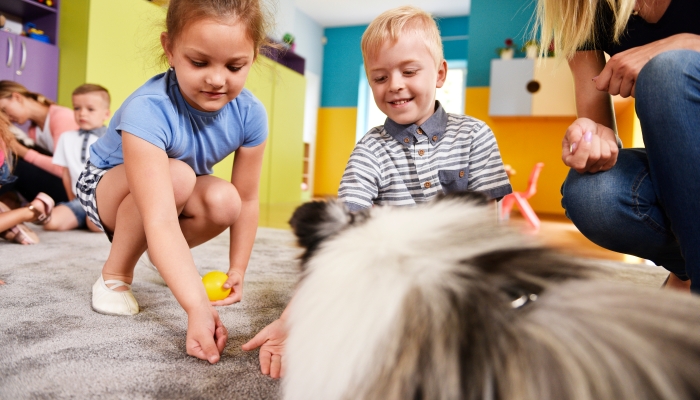 Kids playing with dog in the preschool.