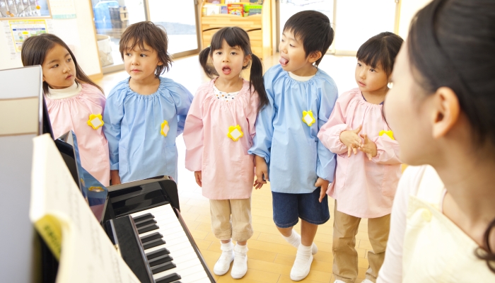 Kindergarten children singing along to the piano of kindergarten teachers.