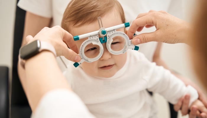 Pediatric eye doctor preparing child for visual acuity test.
