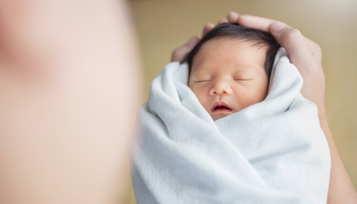 Portrait of young asian father or mother with healthy newborn baby.