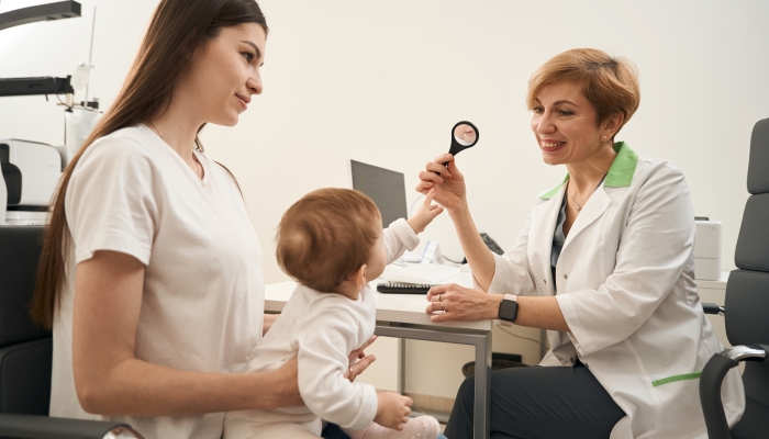 Professional pediatric female ophthalmologist checking infant eyesight.