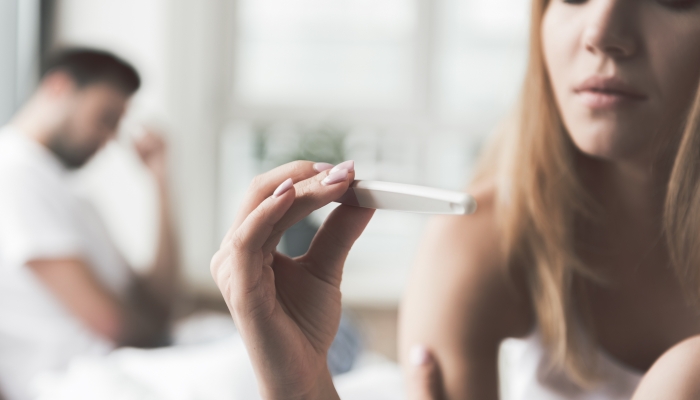 Thoughtful girl undergoing pregnancy test near boyfriend.