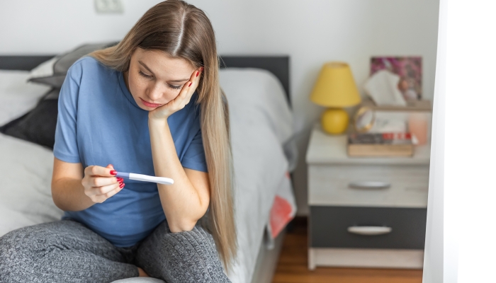 Upset blonde girl checking her recent pregnancy test.