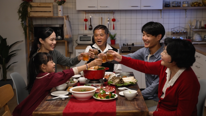 Cheerful chinese family with mixed generation raising glasses to toast new year.