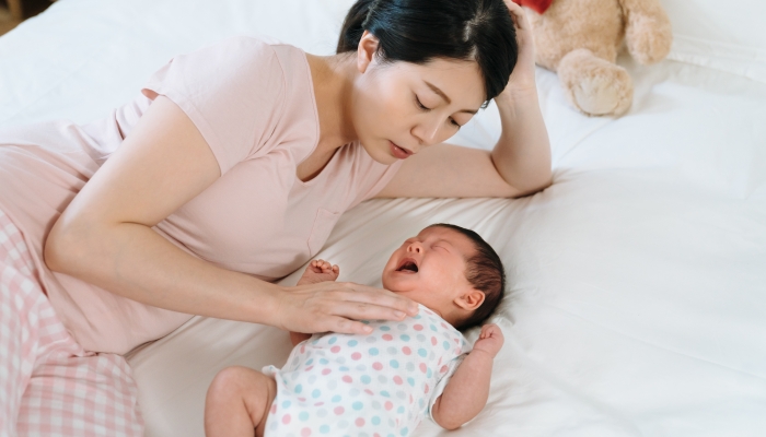 Chinese mother feeling heart ached with pity looking at her baby crying out of illness.